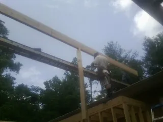 Carpenter setting a ridge beam over a new addition frame — Ice Dam Removal by Roofing Brothers in Clifford