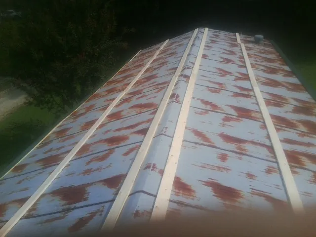 Rusted metal roof panels with new wood purlins before replacement — Storm Damage Roof Repair in Clifford by Roofing Brothers