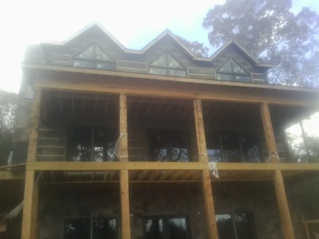 Dormers and porch framing on a large log home under construction — Roof Coating work by our crew in Clifford