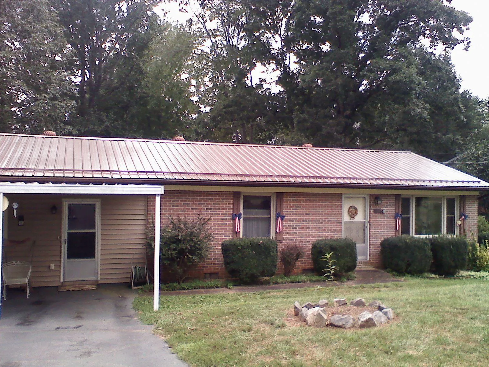 Bronze metal roof and carport on a brick ranch home — Roof Repair work by our crew in Clifford