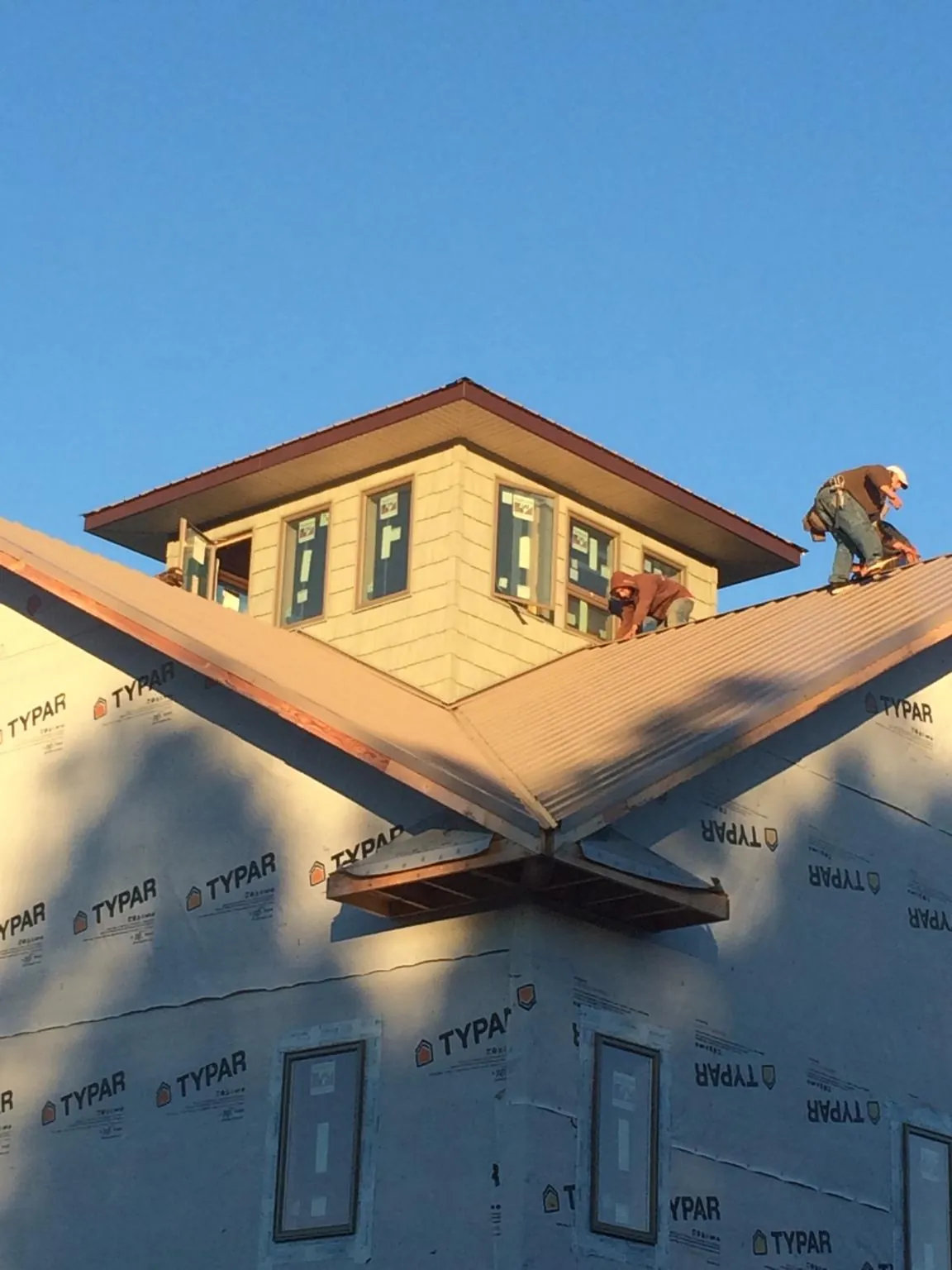 Roofers working around a rooftop cupola on a new metal roof at sunset — Roof Waterproofing in Clifford by Roofing Brothers
